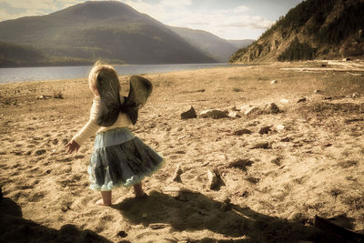 Rear view of boy on beach against sky