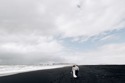 Woman standing on sea shore against sky