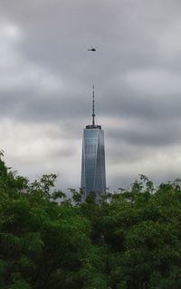 Low angle view of skyscrapers against cloudy sky