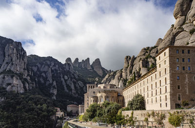 Panoramic view of buildings and mountains against cloudy sky