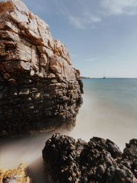 Rock formation on sea against sky long exposure 