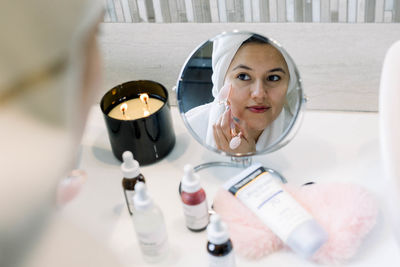 Woman massaging her face with a quartz roller after a facial