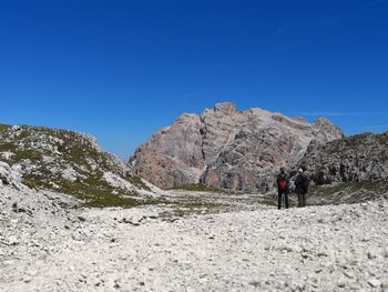 Rear view of two men hiking against dolomites  mountains against clear blue sky