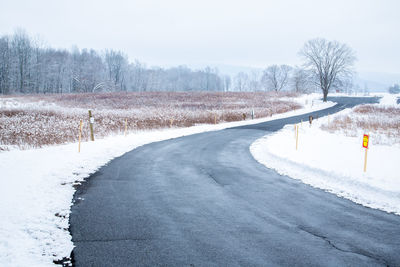 Road amidst frozen trees against sky during winter