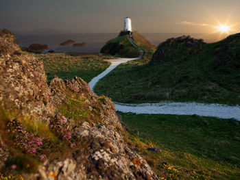 Scenic view of rocks by sea against sky during sunset