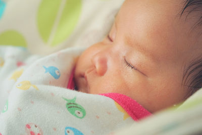 Close-up of baby sleeping on bed