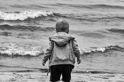 Rear view of boy wading in sea