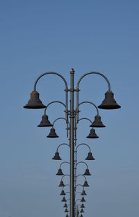 Low angle view of street lights against clear blue sky