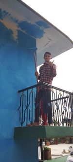 Low angle view of man standing against railing