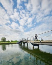 Silhouette people standing on bridge over river against sky