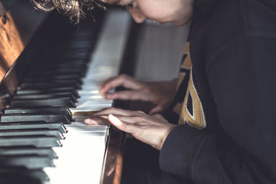 Midsection of boy playing piano