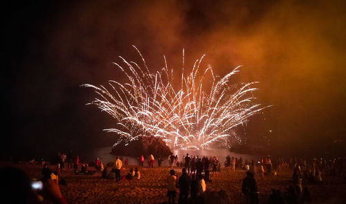 People watching firework display on beach at night