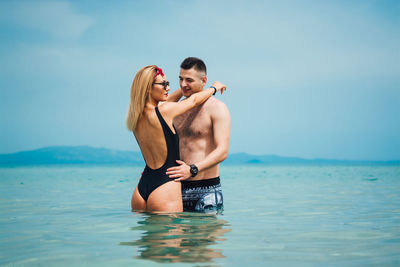 Young couple spending leisure time at beach against sky