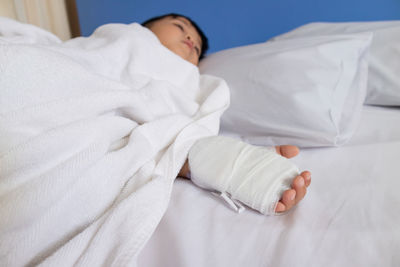 Close-up of boy with bandage on hand lying at home