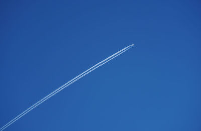 Low angle view of vapor trail against clear blue sky