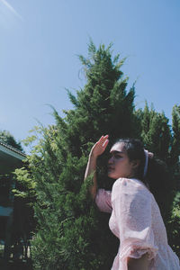 Woman looking away while standing against trees