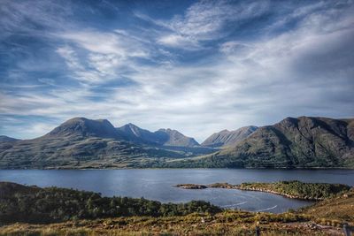 Scenic view of river and rocky mountains against sky