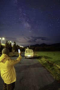 Rear view of man standing on road at night