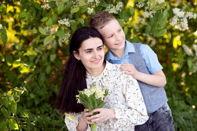 Portrait of smiling young woman standing against plants