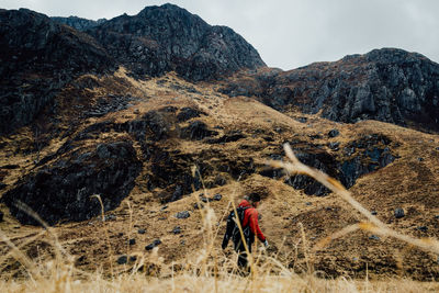 Hiker walking against rocky mountains