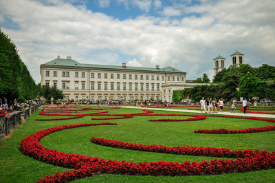 Lawn in front of building against cloudy sky