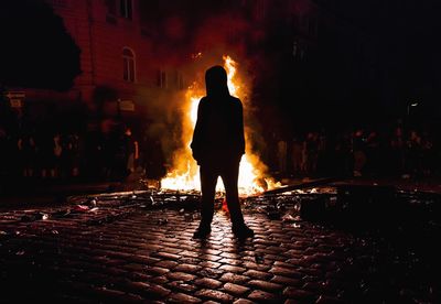 View of silhouette person standing on street at night