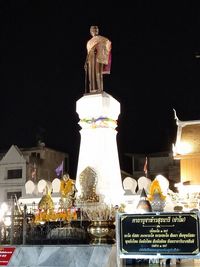 Statue against illuminated building at night