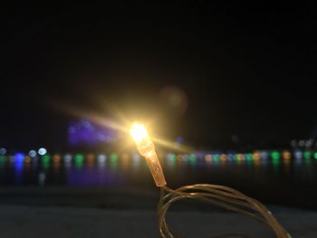 Close-up of illuminated lights against sky at night