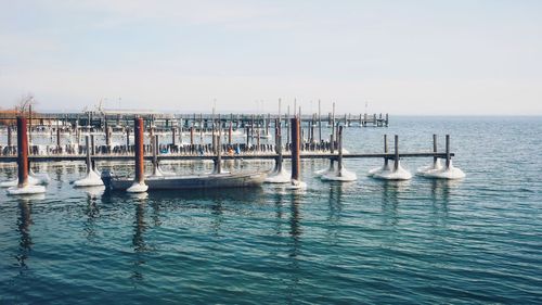 Wooden posts in sea against sky