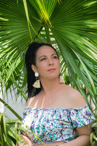 Portrait of young woman standing against plants