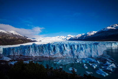 Scenic view of snowcapped mountains against blue sky