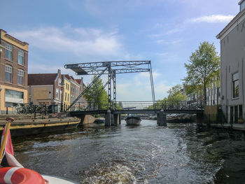 Bridge over river amidst buildings against sky