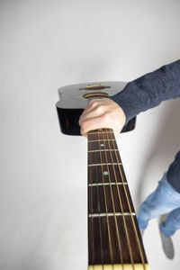 Close-up of hands playing guitar against white background