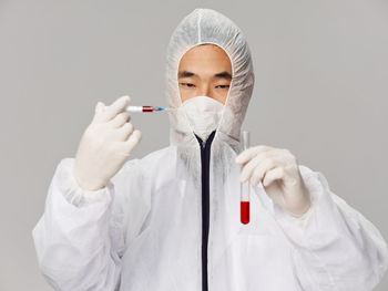 Midsection of doctor holding dentures while standing against white background