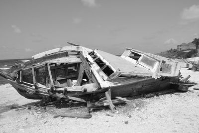 Abandoned boat at beach against sky