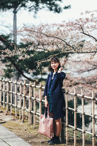 Portrait of smiling young woman standing against trees