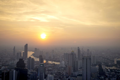 Aerial view of buildings in city during sunset