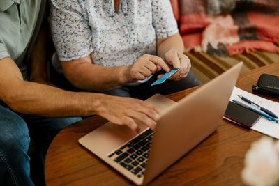 High angle view of elderly woman sitting with male nurse while making online payment through laptop and credit card at h