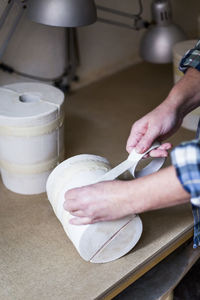 High angle view of female potter taping vase on workbench
