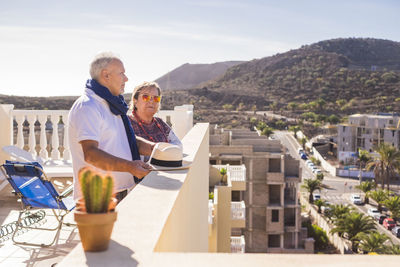 Smiling couple standing on terrace against sky