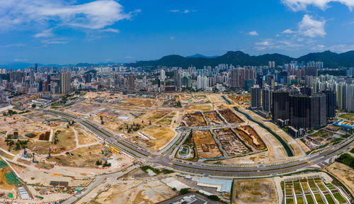 High angle view of city buildings against cloudy sky