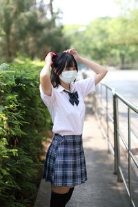 Young woman photographing while standing outdoors