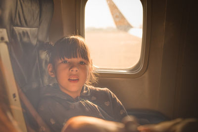 Portrait of girl traveling in airplane during sunset