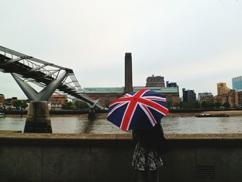 Woman with umbrella against river