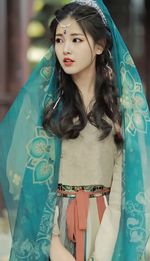 Portrait of young woman standing against store