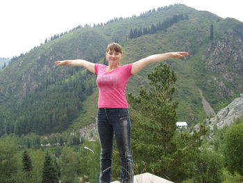 Portrait of carefree young woman standing against mountain