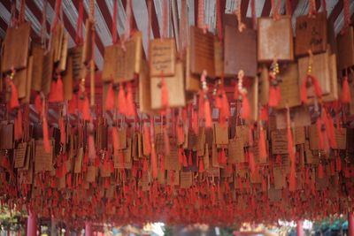 Close-up of red tassels hanging from wooden prayer text placards at temple