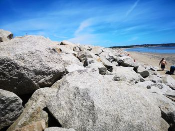 Scenic view of rocks on beach against blue sky