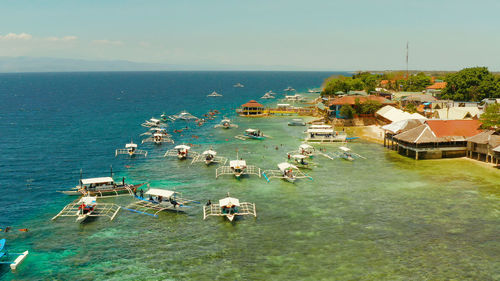 Tourists snorkeling over coral reef with clear blue ocean water, aerial view. moalboal, philippines.