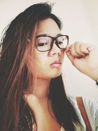 Low angle view of beautiful woman wearing eyeglasses against white wall